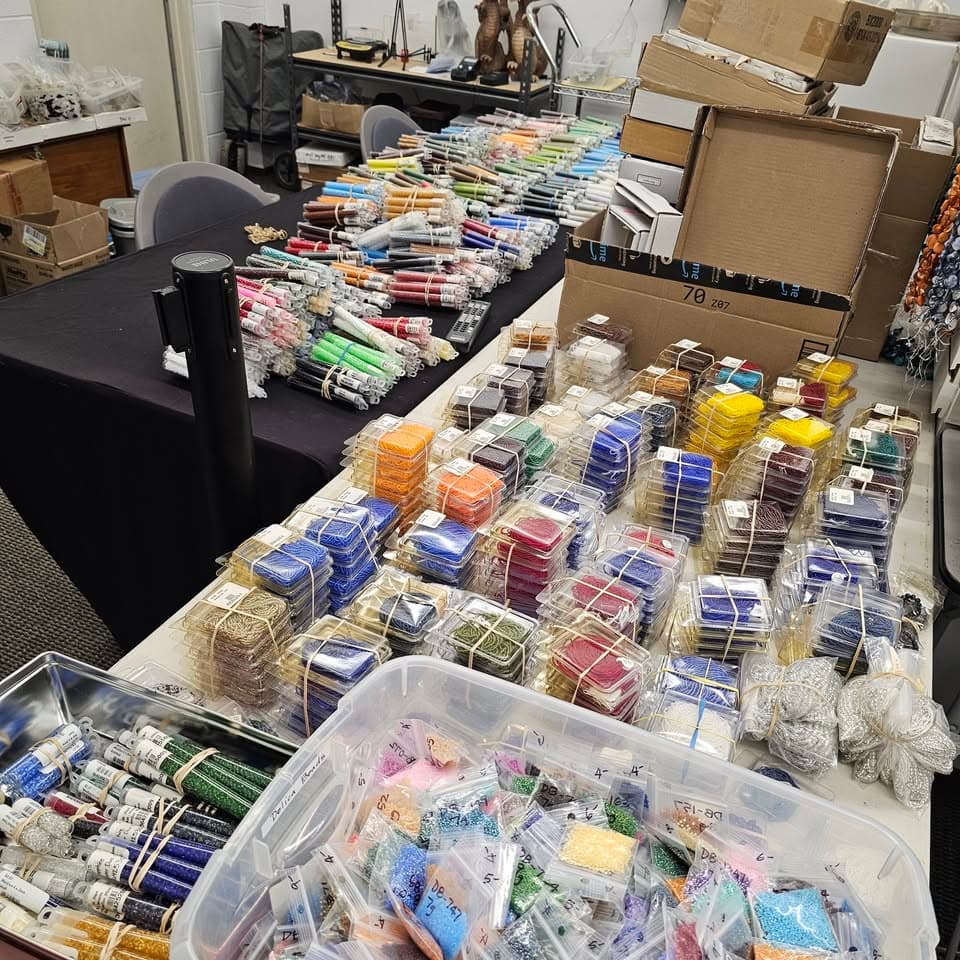 Trays and tubes of seed beads organized by colour on a dark cloth