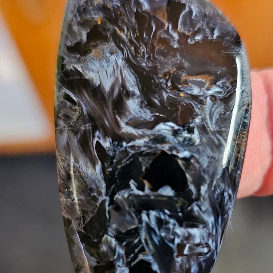 A carved obsidian skull with crystal inclusions, held in hand