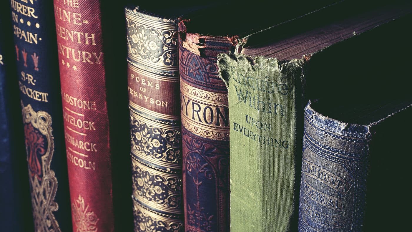 A row of antique hardcover reference books with gilded, lettered spines